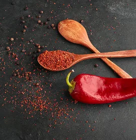 Whole red chili pepper and chili powder on wooden spoons