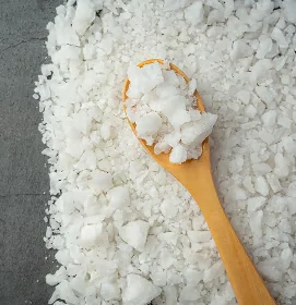 White MSM crystals spread around a wooden spoon