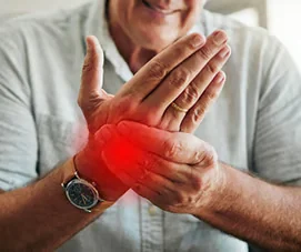Older man in a white shirt massaging his left wrist